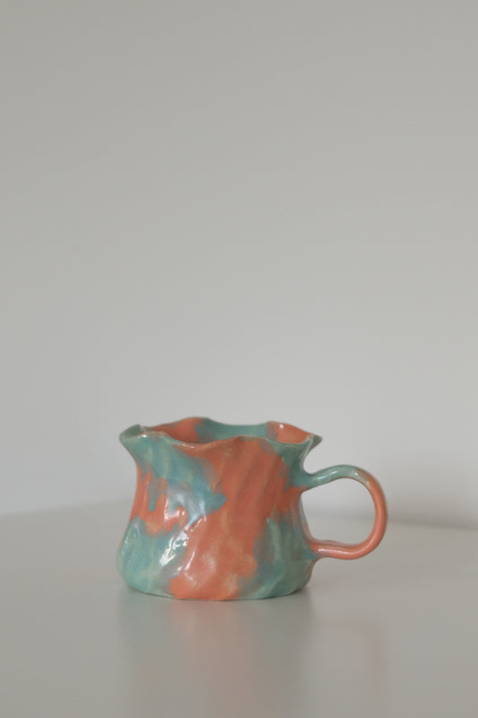 Orange ruffle rim ceramic mug with scalloped edge, front view